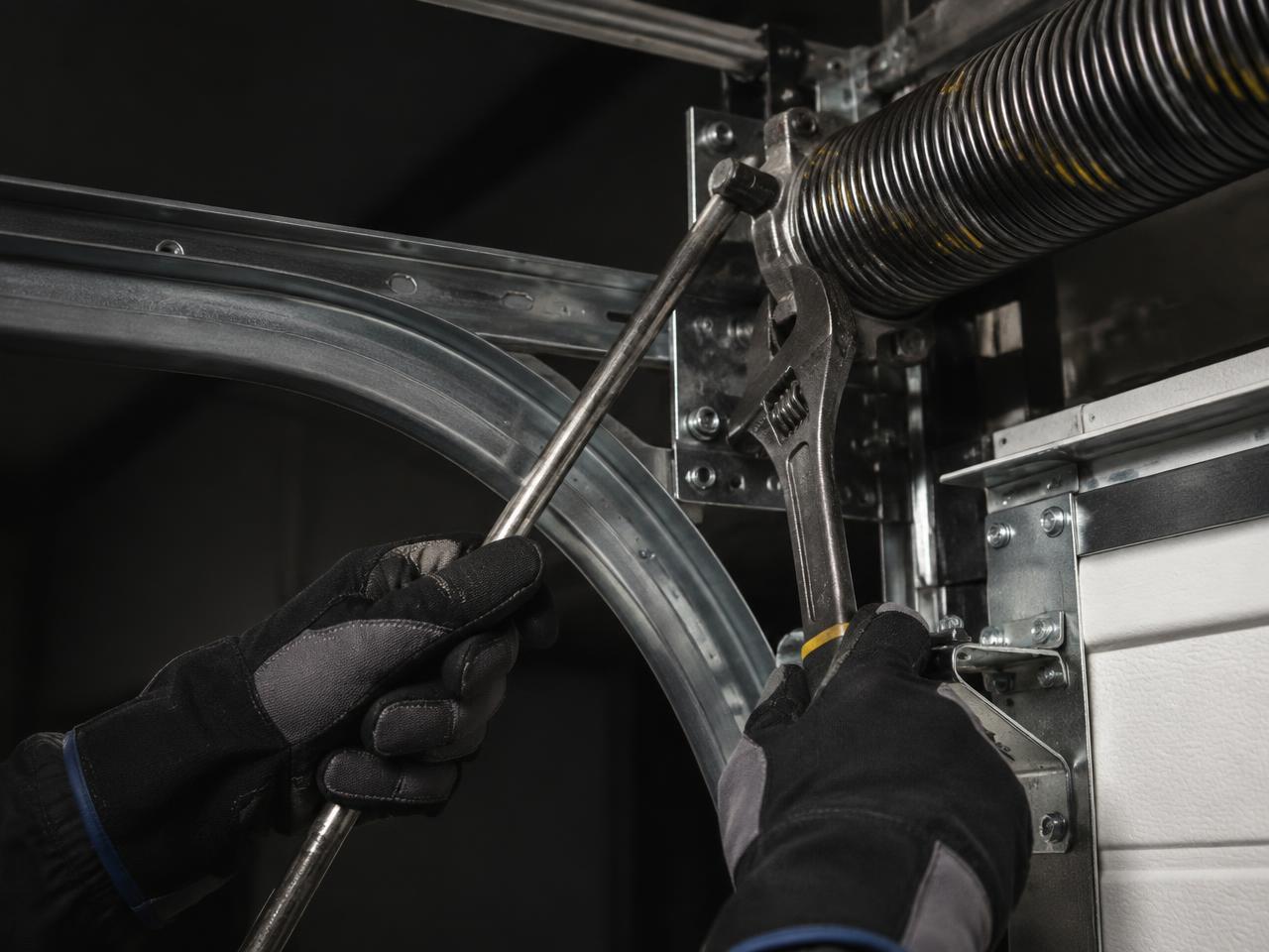 Technician servicing garage door spring and track hardware